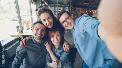 Point of view shot of cheerful friends taking selfie in pizzahouse posing and smiling, laughing and gesturing together. Friendship and happy young people concept. © silverkblack