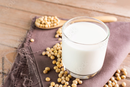 Soy milk in a glass with soybeans on a wooden table organic drink high protein healthy breakfast agricultural produce vegetarian - top view