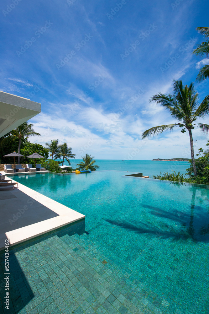 Dramatic clouds and blue sky horizon from the infinity pool with coconut palm trees