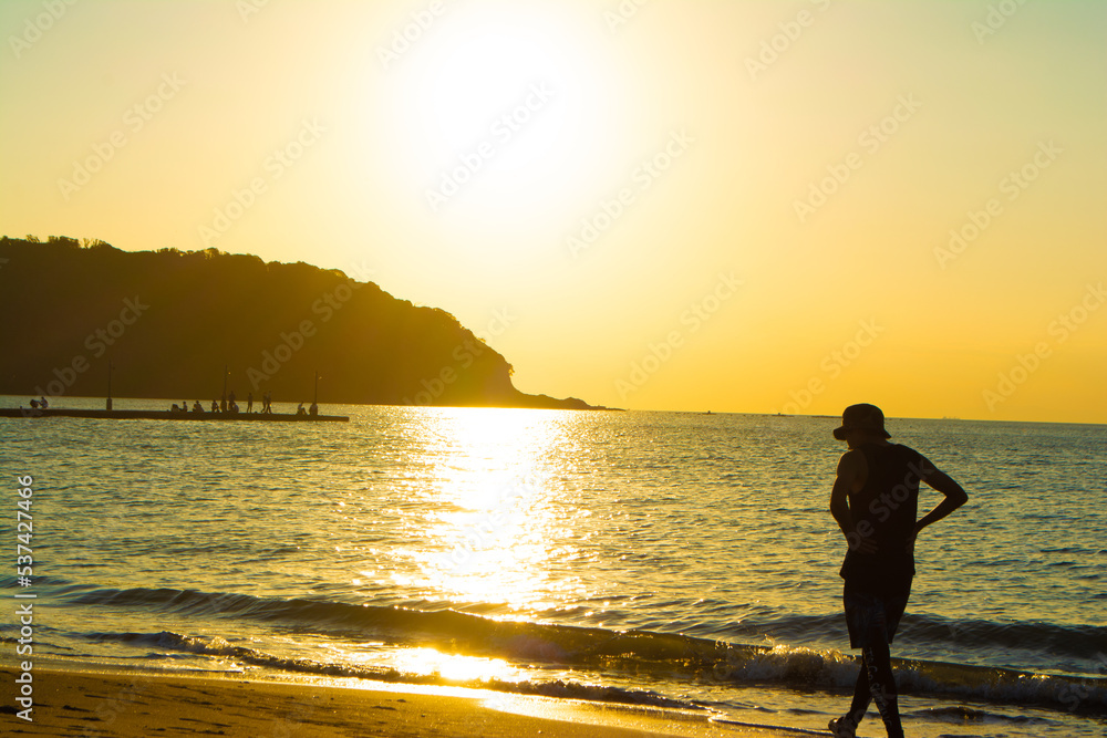 Fototapeta premium 千葉県南房総市の原岡桟橋の夕日と浜辺を散歩する男性