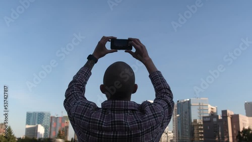 A man photographs the panorama of the city on a smartphone.
