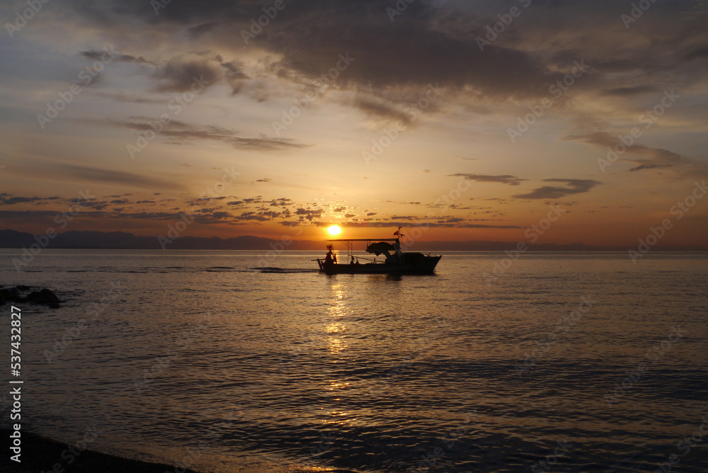 Scenic view on the sea at the sun rise with a boat silhouette