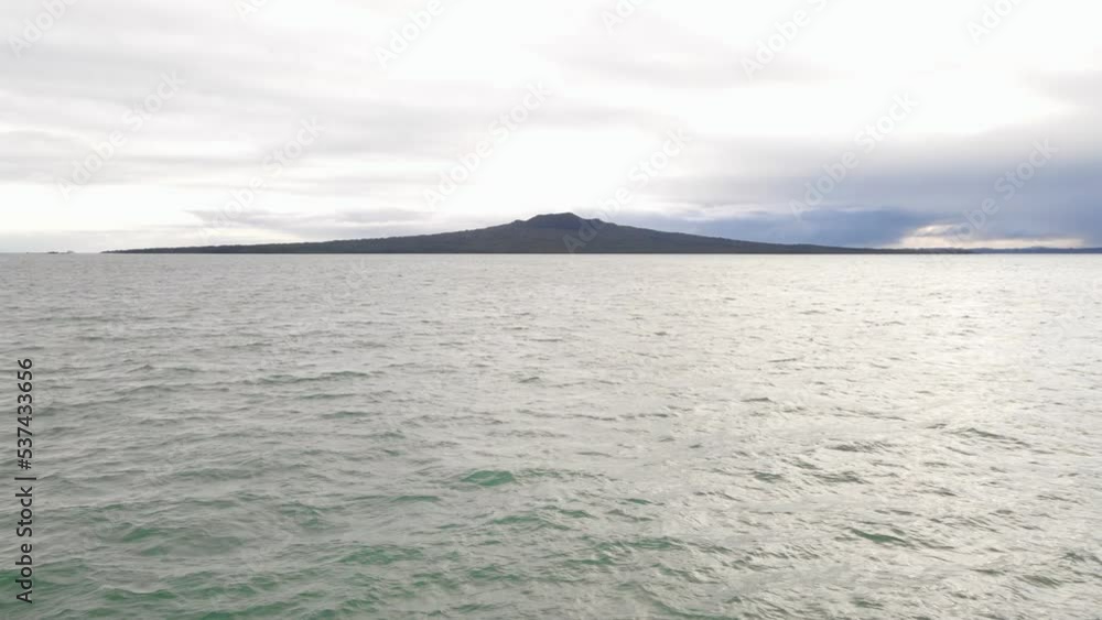 Closing scene of Rangitoto island underneath heavy morning clouds. Wide angle aerial pull back shot Closing scene of Rangitoto island underneath heavy morning clouds. Wide angle aerial pull back shot