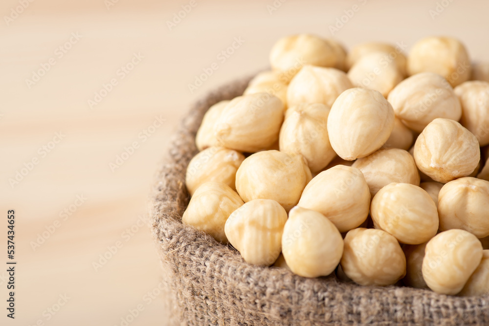Small linen bag of peeled hazelnuts on wooden background. Tasty white hazelnuts, copy space Small linen bag of peeled hazelnuts on wooden background. Tasty white hazelnuts, copy space