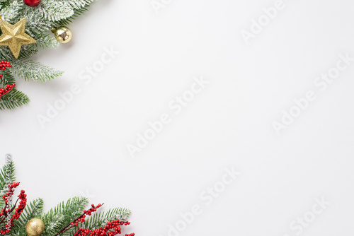 New Year concept. Top view photo of pine branch in snow decorated with baubles star ornament and mistletoe berries on isolated white background with empty space