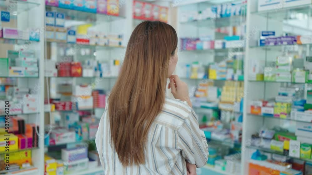 Back view of a woman customer standing and looking products medicines or supplements in the pharmacy