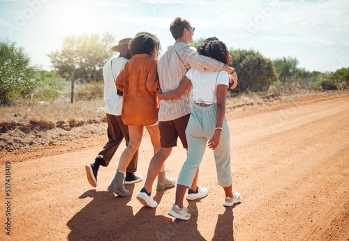 Friends, hug and travel in the countryside for summer vacation walking together on a desert road in nature. People in friendship support, care and love hugging in the safari for holiday walk or trip