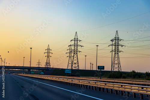 Highway in bright sunlight, power line illuminated by the sun. A beautiful landscape in the golden hour.