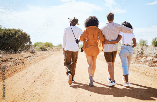 Friends  walking and travel with young people in nature on a sand road with a beautiful desert view of the sky. Vacation  summer and walk with a man and woman group outdoor for a trip or holiday