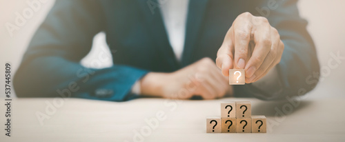 Bilde på lerret Hand hold Wooden cube block in question mark mean what on cement table background, column of wooden blocks with question sign mark
