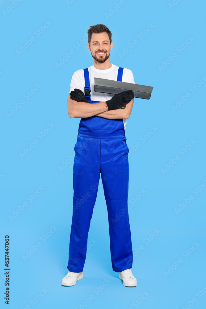 Professional worker with putty knife on light blue background Professional worker with putty knife on light blue background