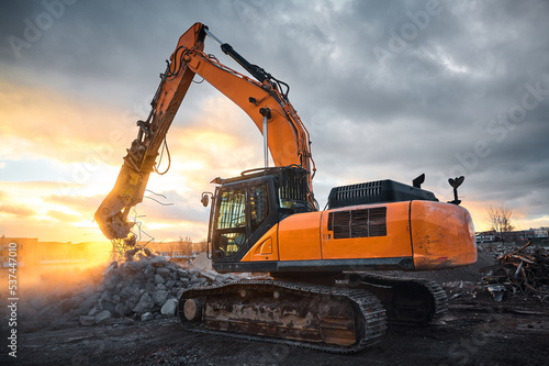 Powerful crusher destroys armored cement leftovers at sunset