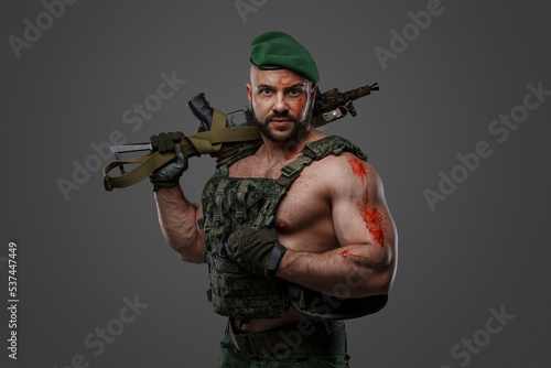 Portrait of troop soldier with muscular build holding rifle looking at camera. © Fxquadro