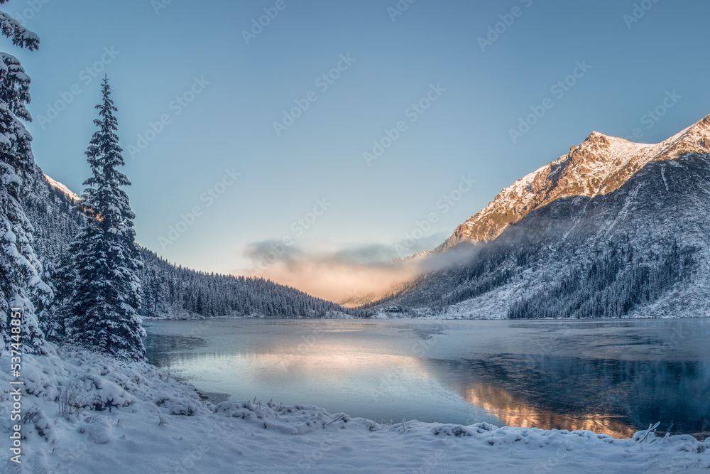 Sunrise above lake in Tatra mountains. Winter frosty morning on the lake Of Eye of the Sea. Famous place in Poland. Travelling in Tatra mountains near lake. Hiking in mountains.