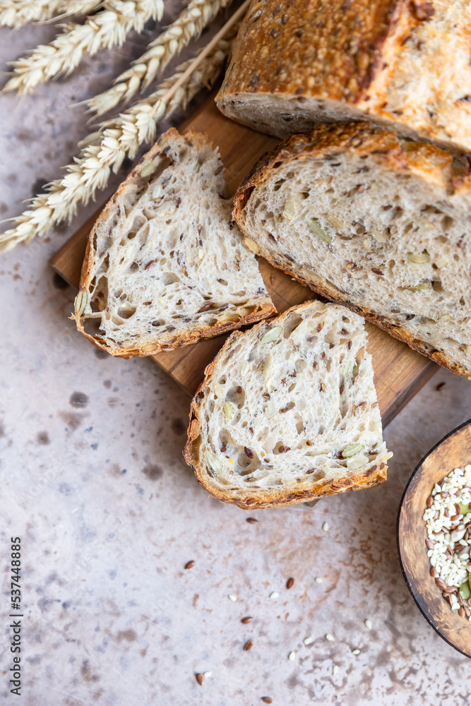Sliced loaf of artisan sourdough bread with multigrain seed. Tartine with honey and seeds, concrete background.
