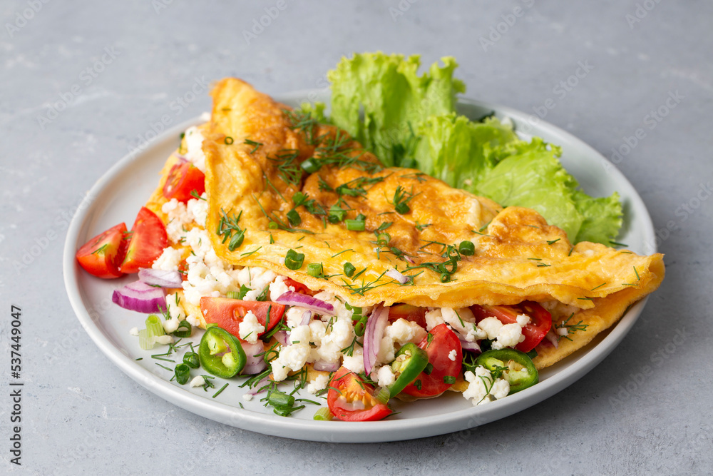 Homemade stuffed omelet on a plate. Egg omelet stuffed with fresh tomatoes, cheese and green parsley. Healthy vegetarian breakfast recipe. Homemade stuffed omelet on a plate. Egg omelet stuffed with fresh tomatoes, cheese and green parsley. Healthy vegetarian breakfast recipe.