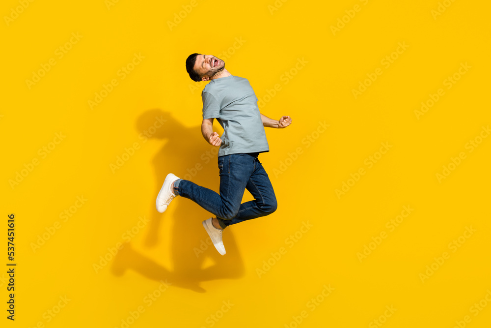 Full length portrait of delighted astonished man jumping celebrate accomplishment isolated on yellow color background