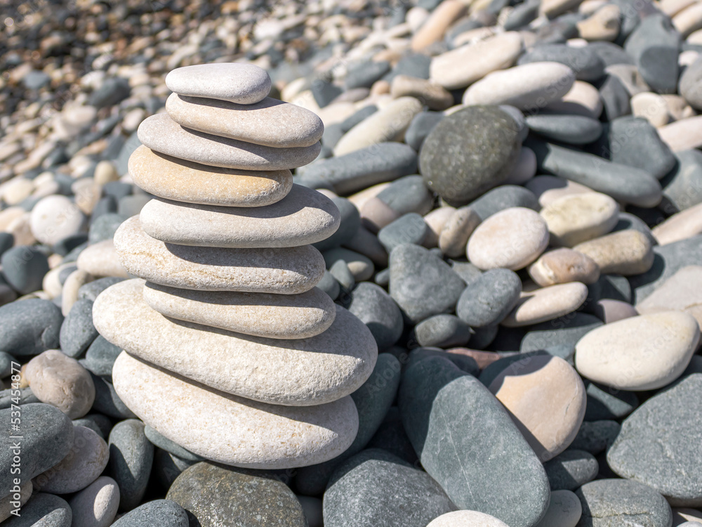 White Zen stone pyramid among beach pebbles White Zen stone pyramid among beach pebbles