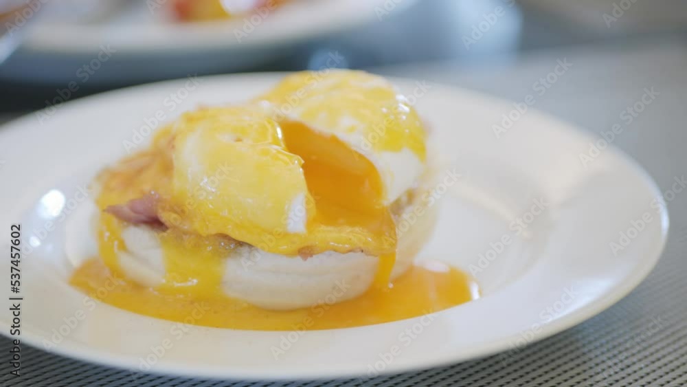 Toast with poached egg and ham close up. Cutting egg benedict with runny egg yolk over toast . Healthy breakfast lunch food Toast with poached egg and ham close up. Cutting egg benedict with runny egg yolk over toast . Healthy breakfast lunch food