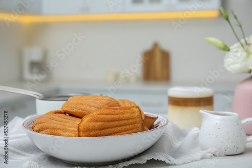 Tasty madeleine cookies on table in kitchen