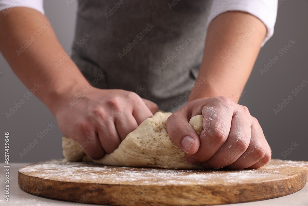 Man kneading dough at table near grey wall, closeup Man kneading dough at table near grey wall, closeup