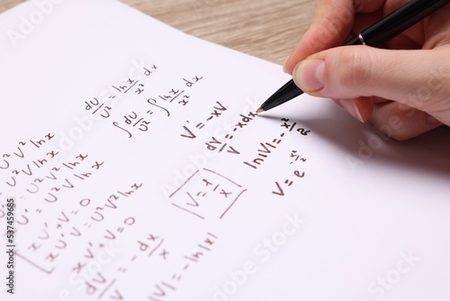 Obraz na plátně Student writing different mathematical formulas on paper, closeup