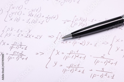 Sheet of paper with mathematical formulas and pen, closeup