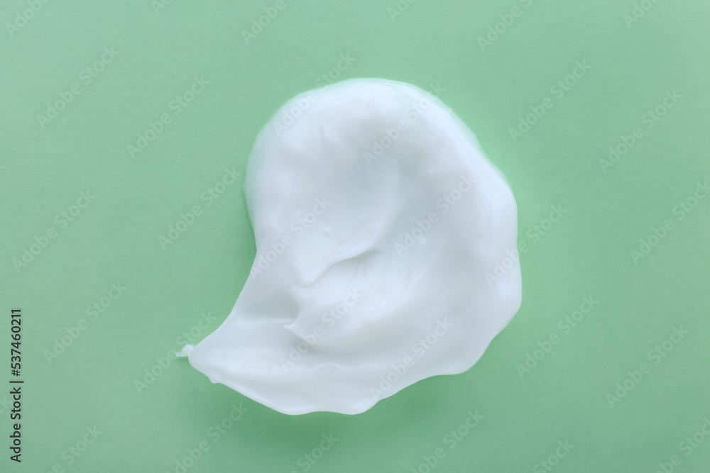 Sample of body cream on light green background, top view