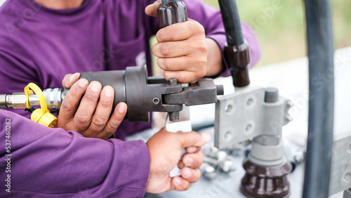 Two electrician builder workers installing high-voltage cable.Hydraulic tongs crimping that is used by workers to crimp ground wires in construction site at oil and gas plant or chemical plant.