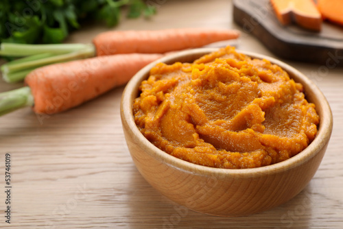 Bowl with tasty carrot puree on wooden table, closeup