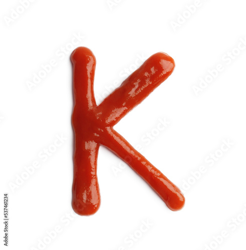 Letter K written with ketchup on white background