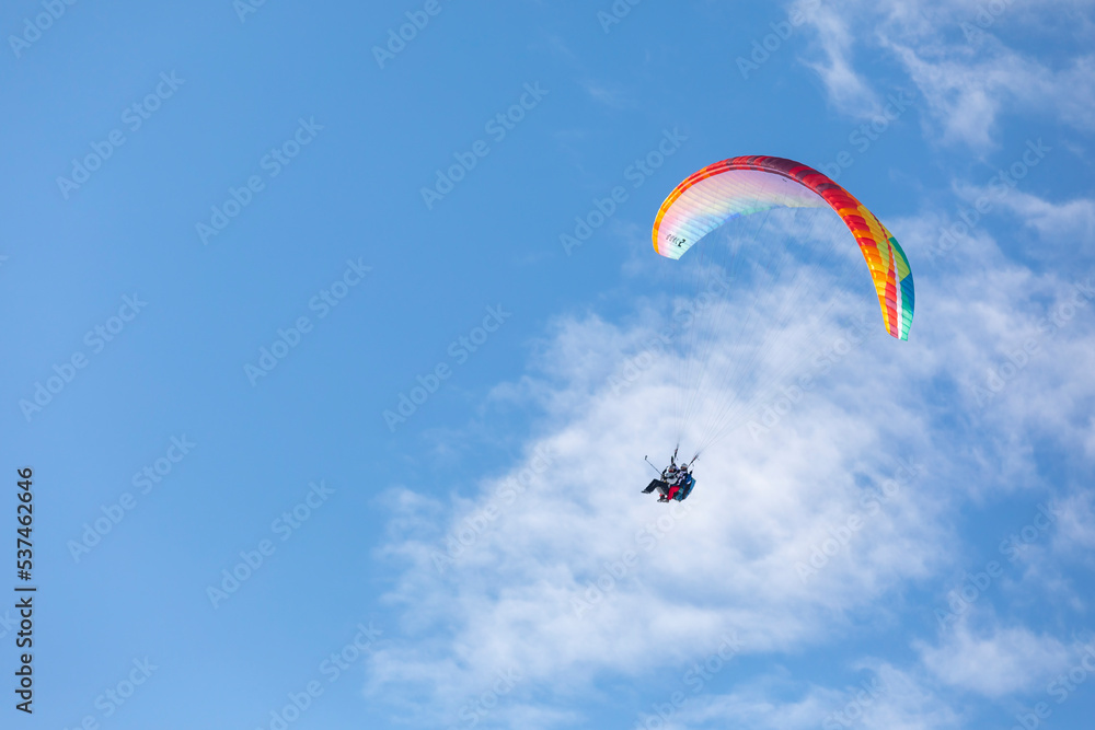 Paragliders in bright blue sky, tandem of instructor and beginner Paragliders in bright blue sky, tandem of instructor and beginner