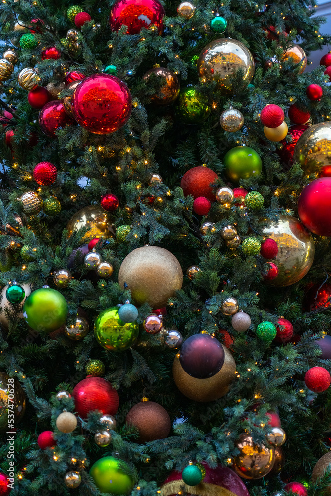 Close up view of Christmas tree branch with decorative balls, toys and shining garland. christmas tree decorations baubles and lights on city market street