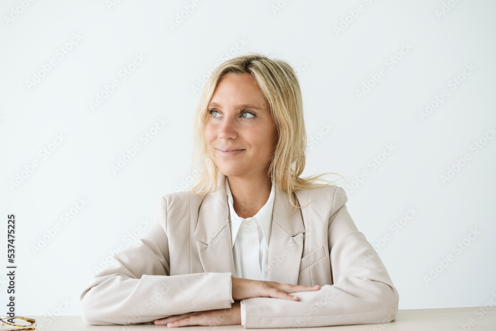 Smiling businesswoman sitting at desk looking away Smiling businesswoman sitting at desk looking away