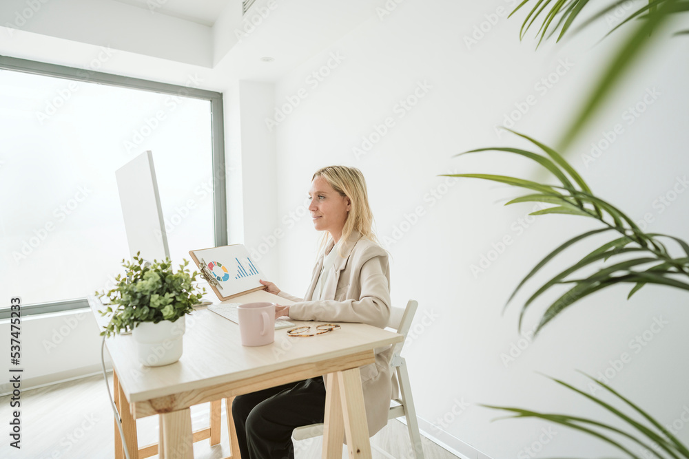 Businesswoman using computer and working on a paper at desk in office Businesswoman using computer and working on a paper at desk in office