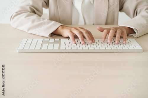 Close-up of businesswoman typing on keyboard at desk photo