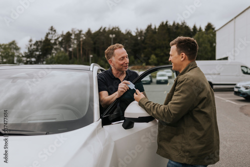 Car salesman giving customer keys to car