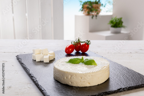 fresh cheese with basil leaf with tomatoes on a rectangular slate board set