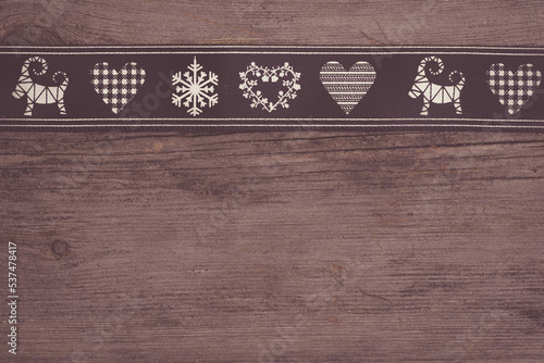 black christmas ribbon with symbols on wooden background with copy space