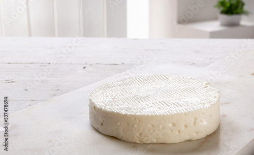fresh cheese on white marble cutting board resting on wooden table, set