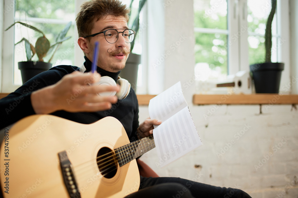 Closeup man with guitar. Handsome musician siiting at home and studying to play guitar. Hobbies and leisure activities. Remote training, online classes Closeup man with guitar. Handsome musician siiting at home and studying to play guitar. Hobbies and leisure activities. Remote training, online classes