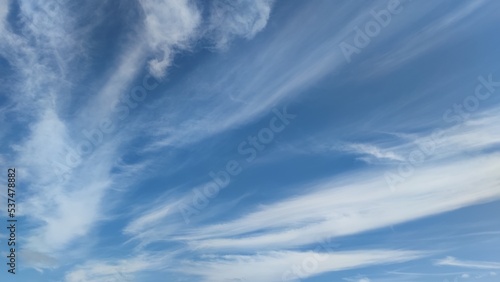 Fototapeta Naklejka Na Ścianę i Meble -  High cirrus clouds in the sky. White elongated translucent clouds hang against the background of a light blue sky. They seem to be smeared along the length of the entire sky.