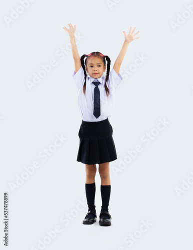 Asian junior school girl in student uniform standing full length and hands up on white background. Back to school concept