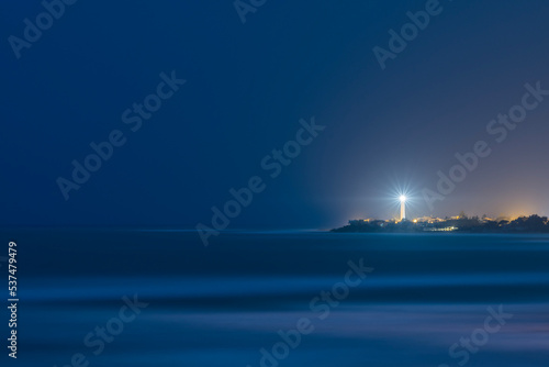 Faro di notte su mare calmo photo