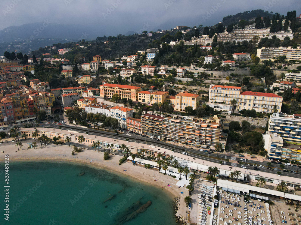 Aerial view of Menton in French Riviera from above. Drone view of France Cote d'Azur sand beach beneath the colorful old town of Menton. Small color houses near the border with Italy, Europe.