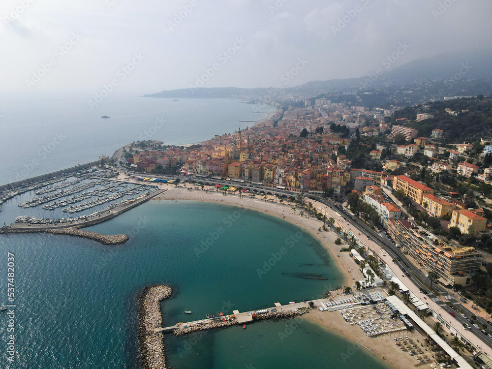 Aerial view of Menton in French Riviera from above. Drone view of France Cote d'Azur sand beach beneath the colorful old town of Menton. Small color houses near the border with Italy, Europe. Aerial view of Menton in French Riviera from above. Drone view of France Cote d'Azur sand beach beneath the colorful old town of Menton. Small color houses near the border with Italy, Europe.
