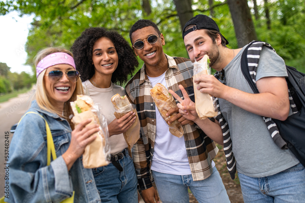 Young people eating sandwiches and looking joyful Young people eating sandwiches and looking joyful