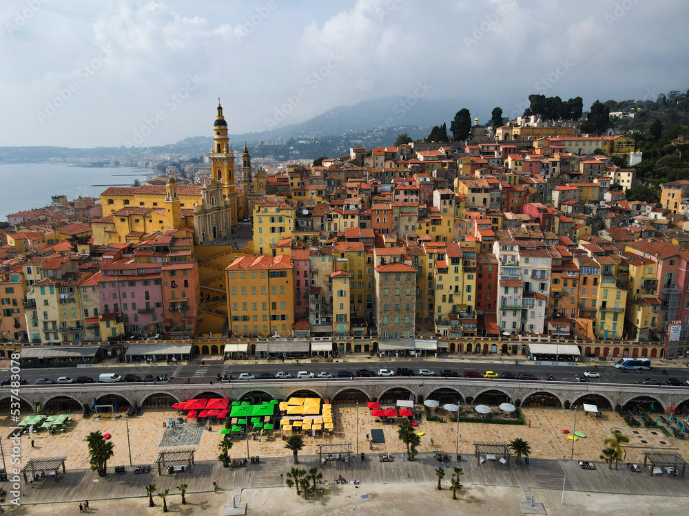 Fototapeta premium Aerial view of Menton in French Riviera from above. Drone view of France Cote d'Azur sand beach beneath the colorful old town of Menton. Small color houses near the border with Italy, Europe.