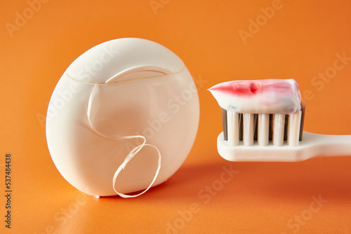 Toothbrush with toothpaste and dental floss on an orange background. Dental care. Oral hygiene.