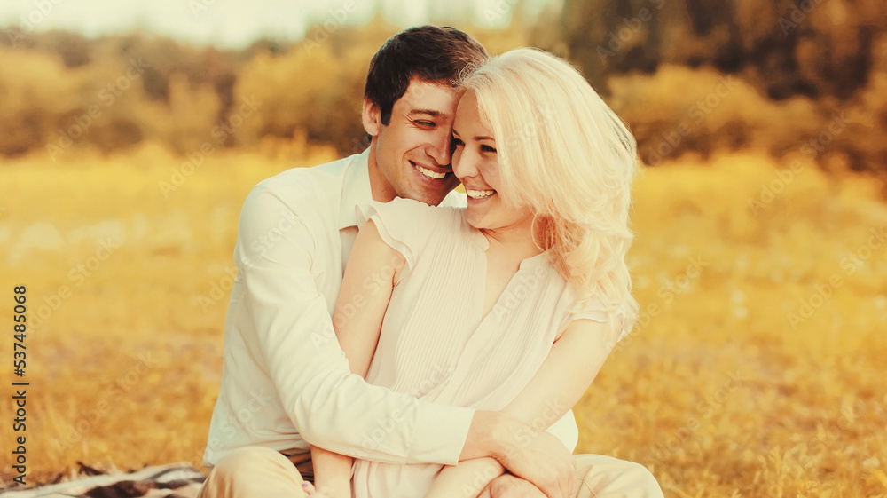 Portrait of happy laughing young couple hugging on the grass in the park
